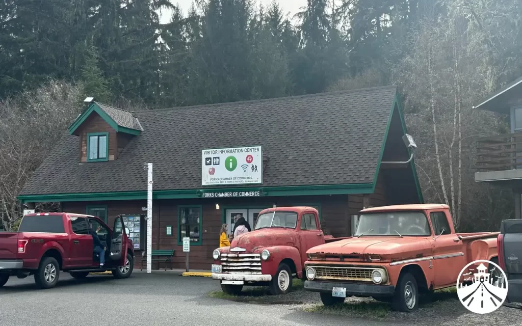 Two replica red trucks representing Bella Swan’s vehicles from the Twilight book and movie, parked outside the Forks Chamber of Commerce.