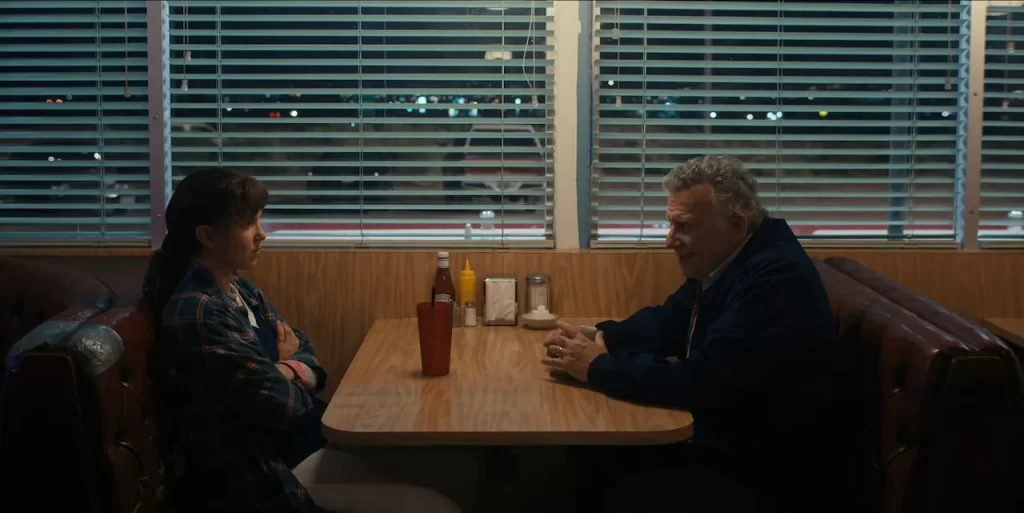 Eleven and Dr. Sam Owens seated in a booth at the County Line Café in Stranger Things Season 4.