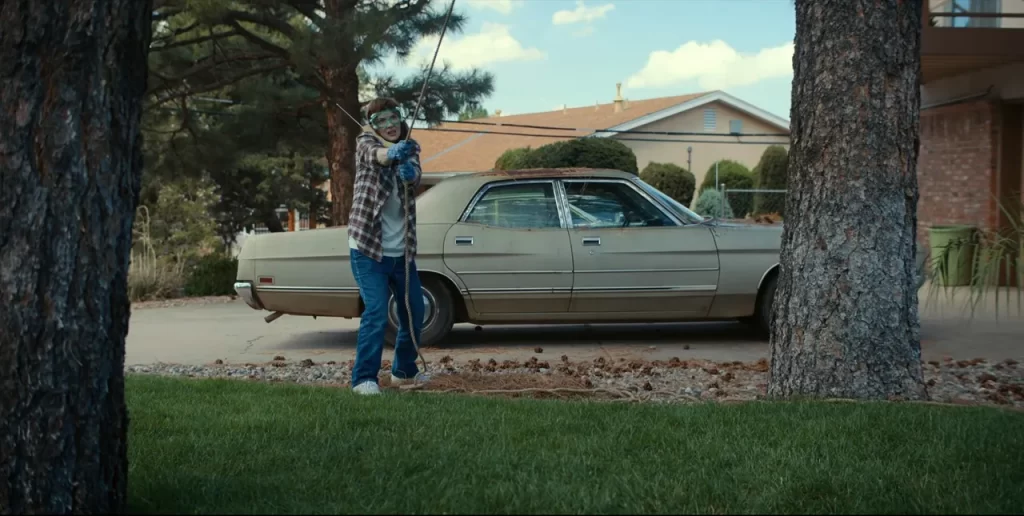 Joyce Byers lifting the doll between trees in Stranger Things Season 4.