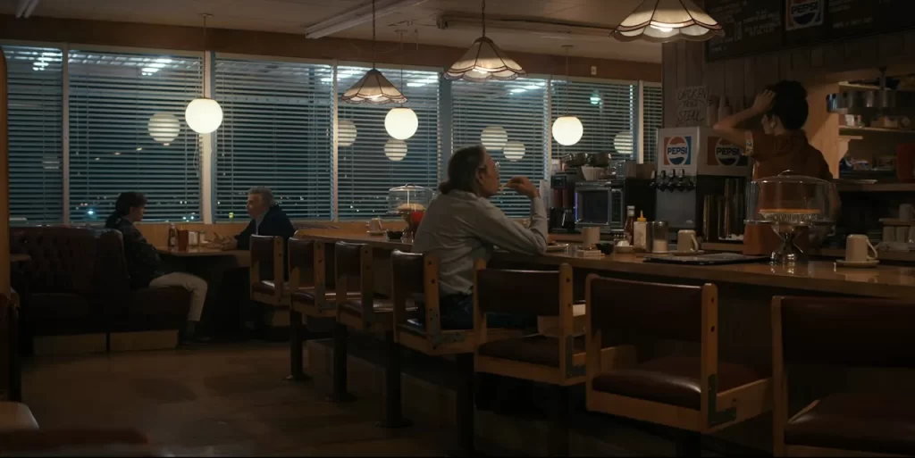 Wide shot of the County Line Café interior with Eleven, Dr. Owens, and a waitress in Stranger Things Season 4.