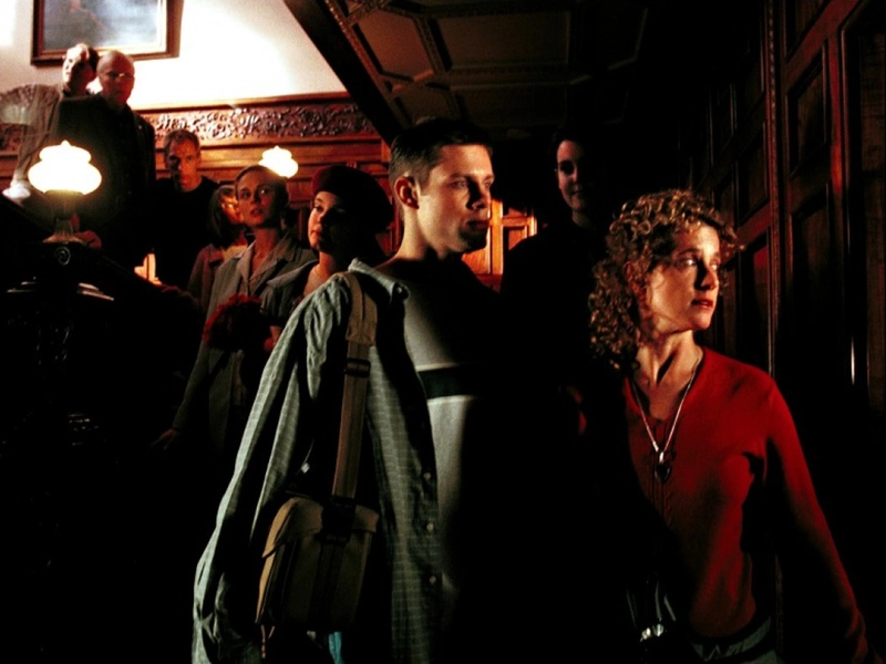 The group gathers on the grand staircase inside Rose Red, pausing together during their exploration of the mansion.